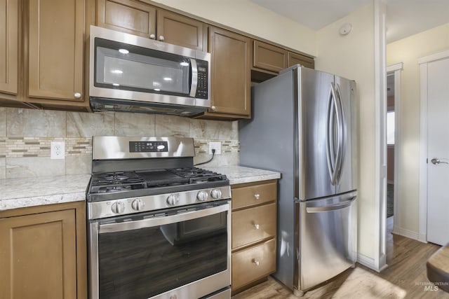 kitchen featuring tasteful backsplash, appliances with stainless steel finishes, and light wood-type flooring