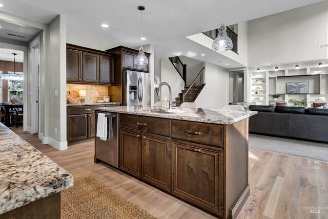 2043 E Lodge Trail Dr, Meridian, ID 83642 - kitchen featuring a sink, stainless steel appliances, dark brown cabinets, light wood-style floors, and light stone countertops