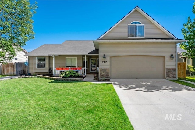 traditional home featuring fence, driveway, a porch, a front yard, and stone siding