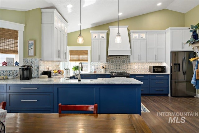 kitchen featuring white cabinets, a sink, lofted ceiling, blue cabinetry, and appliances with stainless steel finishes