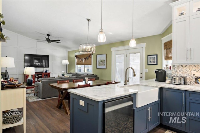 kitchen featuring a peninsula, stainless steel dishwasher, a sink, lofted ceiling, and dark wood-type flooring
