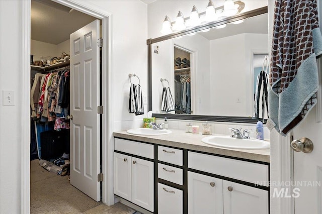 full bath featuring a walk in closet, a sink, and double vanity