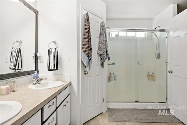 full bathroom featuring double vanity, a shower stall, tile patterned flooring, and a sink