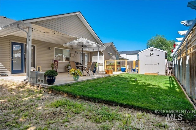 rear view of house featuring a lawn, a fenced backyard, an outbuilding, a patio, and a storage unit