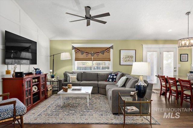 living area with vaulted ceiling, wood finished floors, and ceiling fan with notable chandelier