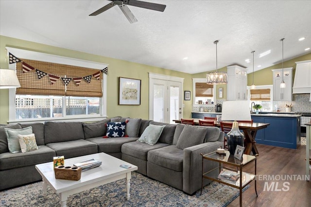 living room featuring dark wood finished floors, lofted ceiling, a wealth of natural light, and ceiling fan with notable chandelier