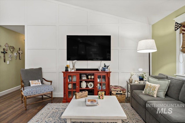 living room featuring vaulted ceiling, wood finished floors, a decorative wall, and baseboards