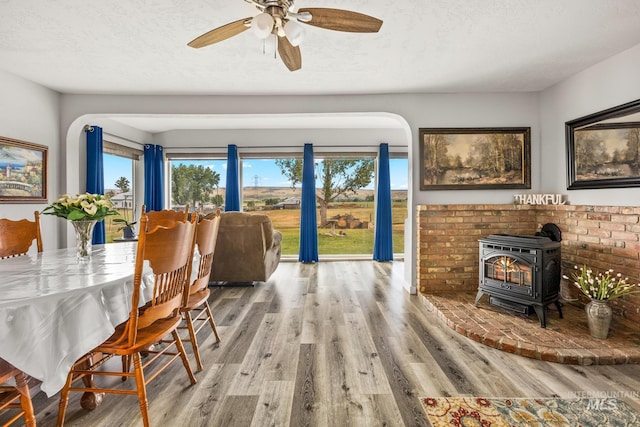 2208 Keithley Creek Rd, Midvale, ID 83645 - dining space with a wood stove, wood finished floors, ceiling fan, a textured ceiling, and arched walkways