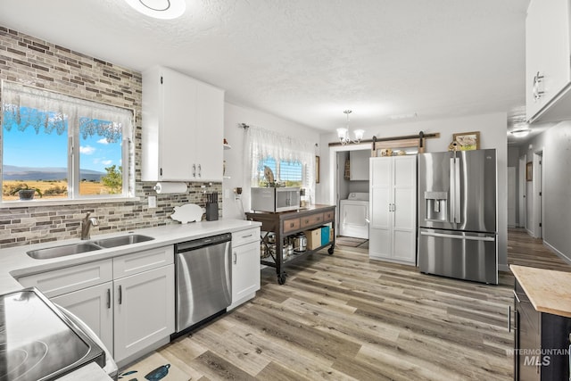 2208 Keithley Creek Rd, Midvale, ID 83645 - kitchen with appliances with stainless steel finishes, washer / dryer, a barn door, a textured ceiling, and white cabinets