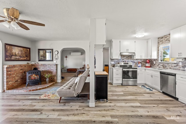2208 Keithley Creek Rd, Midvale, ID 83645 - kitchen with stainless steel appliances, a wall unit AC, a wood stove, light wood-style floors, and a textured ceiling
