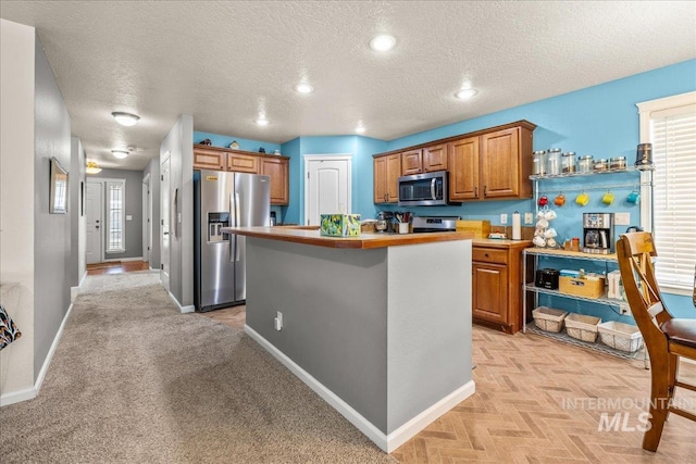 2030 W Cabot Ave, Nampa, ID 83686 - kitchen featuring a kitchen island, baseboards, light countertops, brown cabinetry, and stainless steel appliances