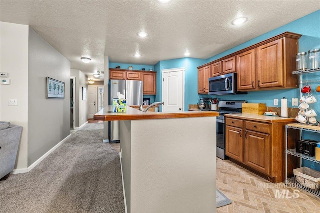 2030 W Cabot Ave, Nampa, ID 83686 - kitchen with a center island with sink, appliances with stainless steel finishes, brown cabinetry, light countertops, and baseboards