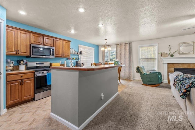2030 W Cabot Ave, Nampa, ID 83686 - kitchen with pendant lighting, a center island with sink, appliances with stainless steel finishes, brown cabinetry, and light countertops
