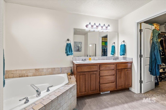2030 W Cabot Ave, Nampa, ID 83686 - bathroom with a sink, a walk in closet, a garden tub, and a textured ceiling
