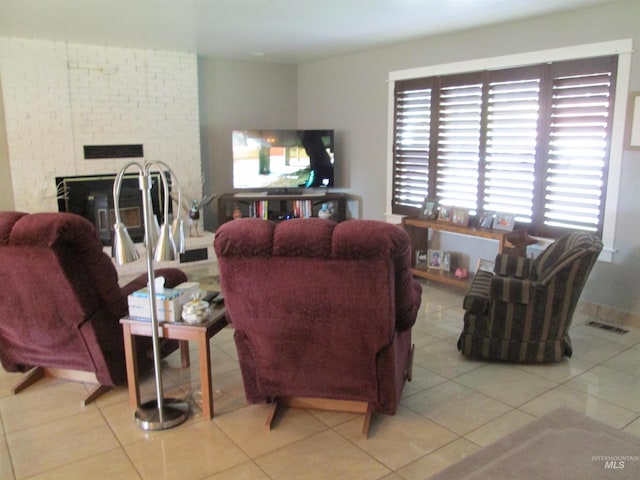 tiled living area with a brick fireplace and visible vents