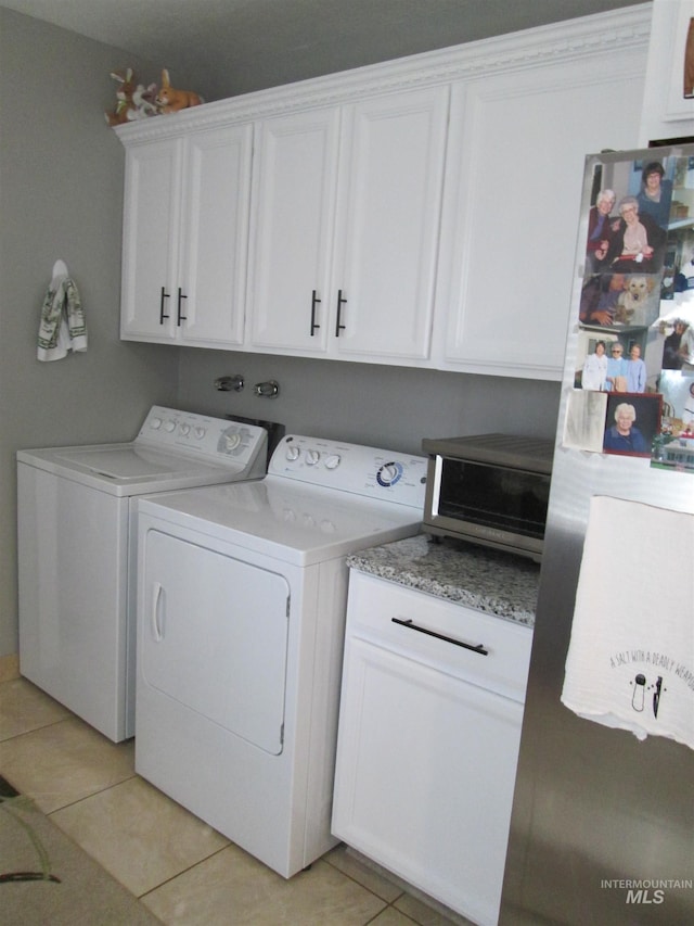 laundry area featuring a toaster, cabinet space, washing machine and clothes dryer, and light tile patterned floors