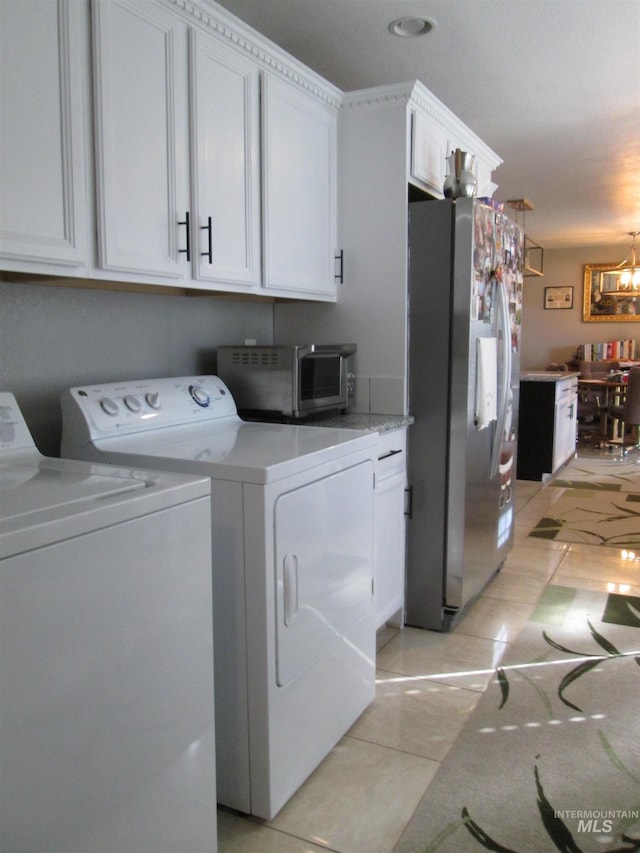 laundry area with light tile patterned floors, a notable chandelier, cabinet space, and independent washer and dryer