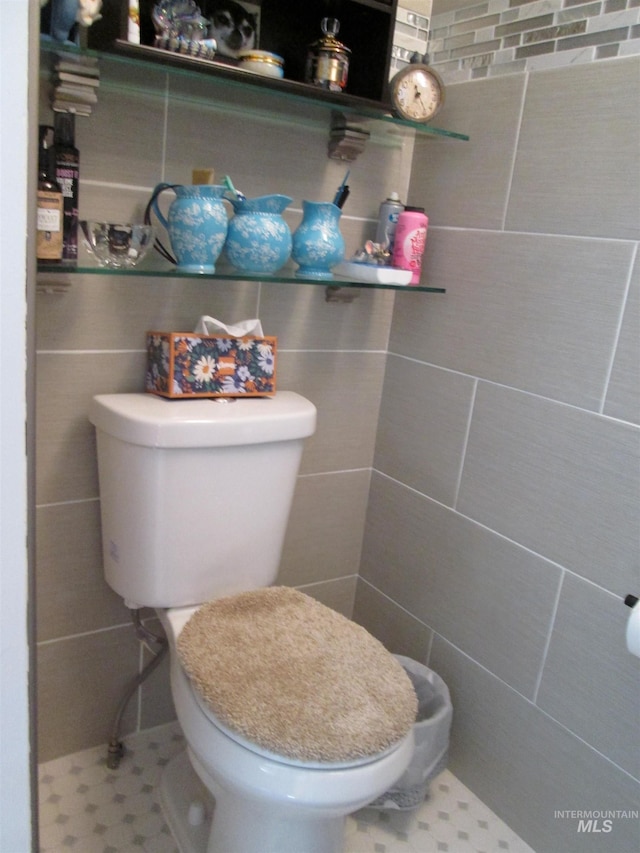 bathroom with toilet and tile walls