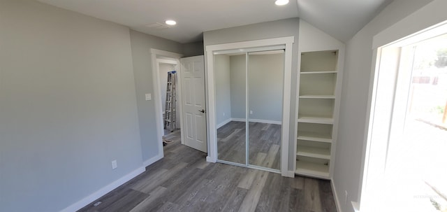 unfurnished bedroom with a closet, dark hardwood / wood-style floors, and lofted ceiling