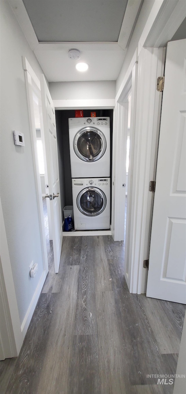 laundry area with stacked washing maching and dryer and dark hardwood / wood-style flooring