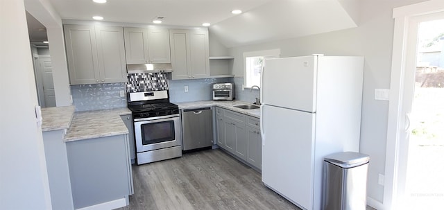 kitchen featuring lofted ceiling, stainless steel appliances, sink, and gray cabinetry