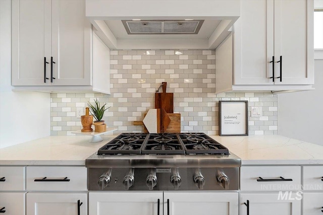 kitchen featuring custom range hood, tasteful backsplash, and light stone counters