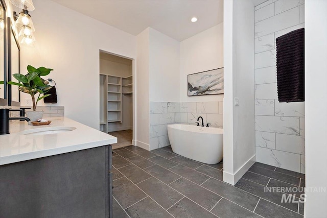 bathroom with tile walls, a washtub, tile patterned flooring, and vanity