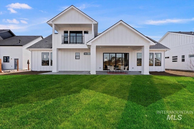 rear view of property with a yard, a balcony, and a patio area