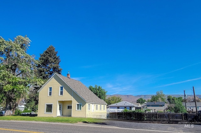1603 11th Ave, Lewiston, ID 83501 - view of front of home with fence, a chimney, a mountain view, and roof with shingles