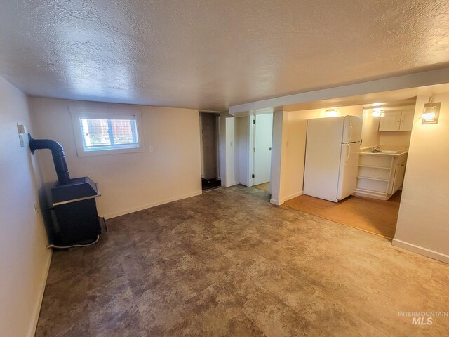 1603 11th Ave, Lewiston, ID 83501 - unfurnished living room with a textured ceiling, baseboards, a wood stove, a sink, and tile patterned floors