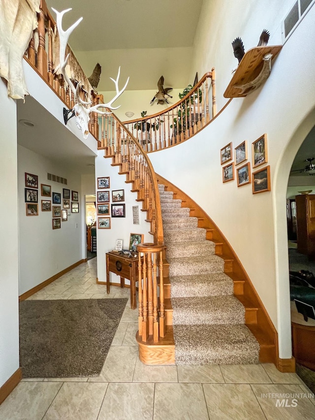 stairway with a high ceiling and tile patterned floors