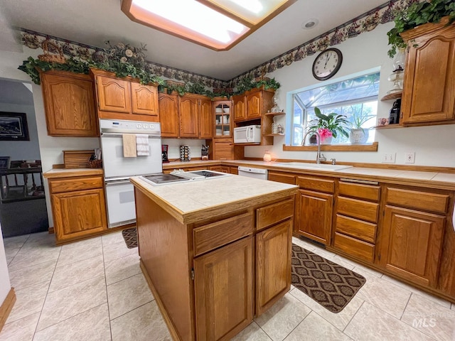 kitchen with tile countertops, a center island, sink, light tile patterned floors, and white appliances