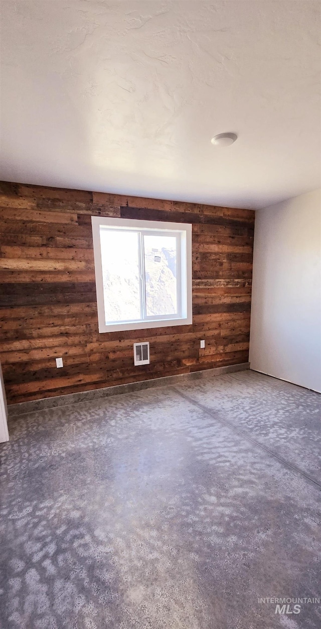 spare room with wooden walls and dark colored carpet