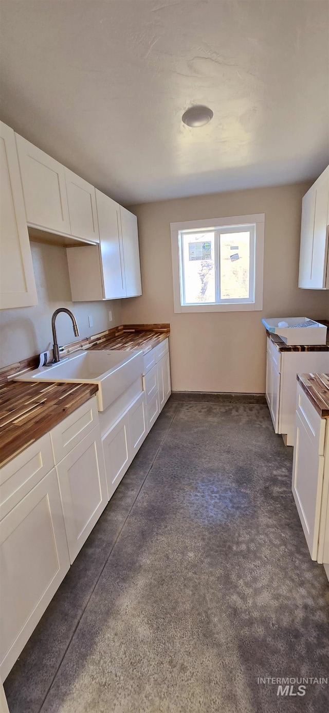 kitchen featuring wood counters, sink, and white cabinetry