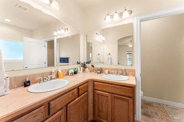 bathroom featuring double vanity, ceiling fan, toilet, and baseboards