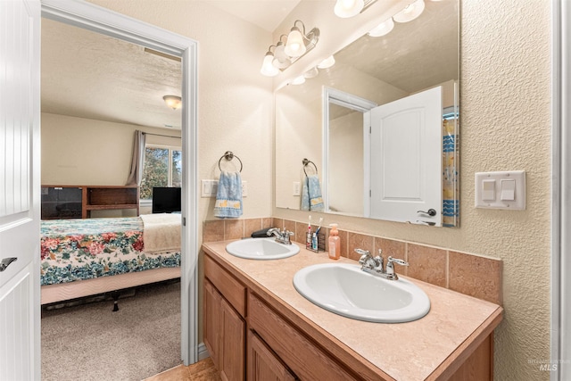 bathroom with connected bathroom, double vanity, and a textured wall