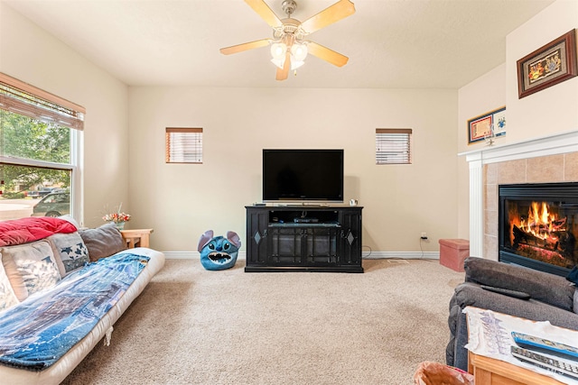 carpeted living area featuring baseboards, a tiled fireplace, and a ceiling fan