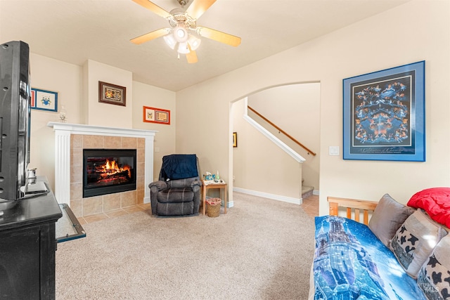 living room featuring arched walkways, carpet floors, ceiling fan, and a fireplace