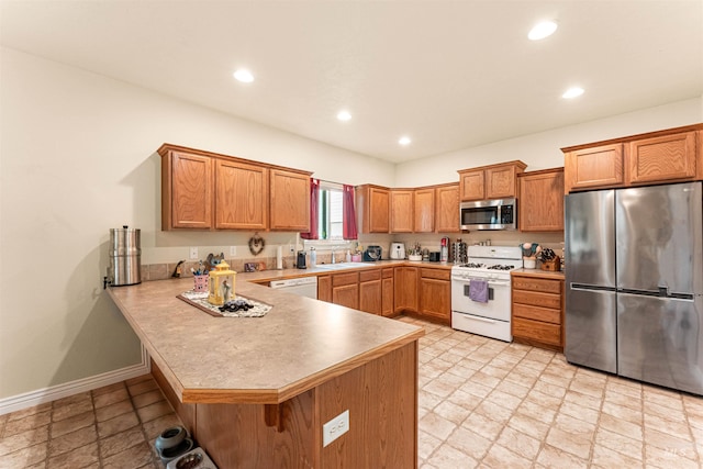 kitchen featuring appliances with stainless steel finishes, a sink, a peninsula, a breakfast bar area, and light countertops