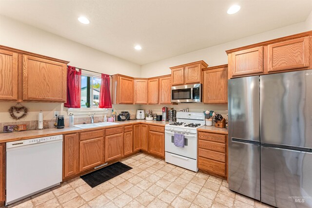 kitchen with appliances with stainless steel finishes, a sink, light countertops, and recessed lighting
