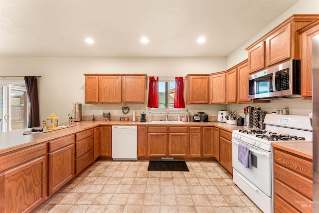 kitchen with white appliances, recessed lighting, light countertops, light stone finish floors, and brown cabinets