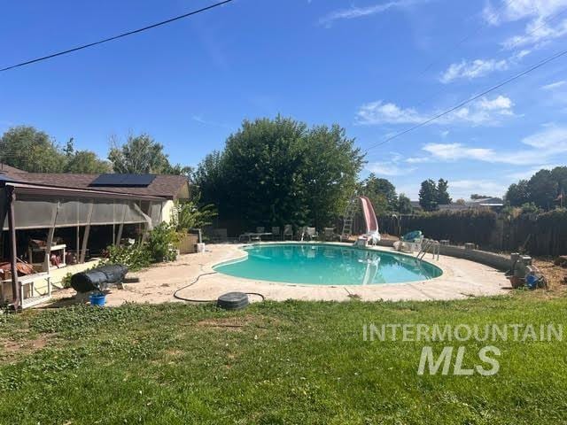 view of swimming pool featuring a patio, a yard, and a water slide