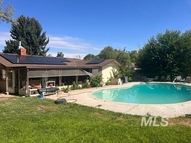 view of pool featuring a lawn, a sunroom, and a patio area