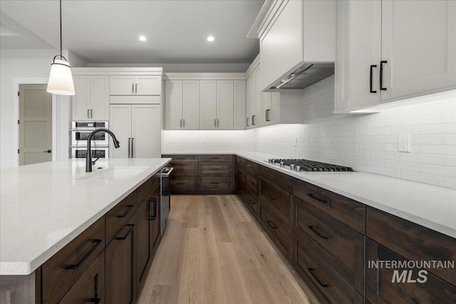 kitchen featuring tasteful backsplash, stainless steel appliances, sink, pendant lighting, and white cabinets