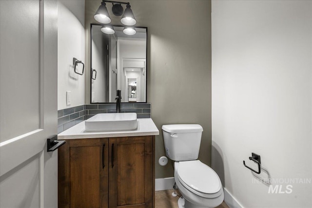 bathroom with decorative backsplash, vanity, and toilet