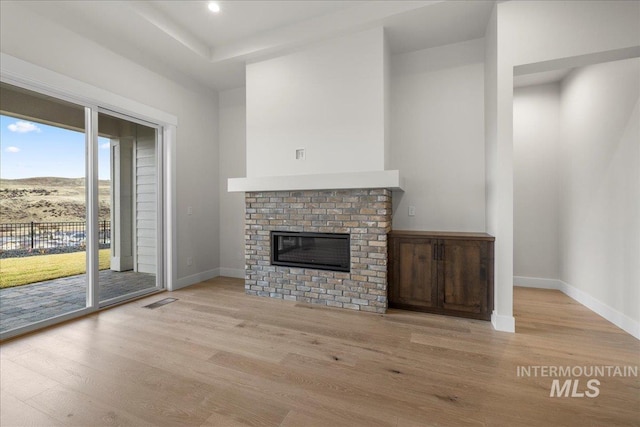 unfurnished living room with a fireplace and light wood-type flooring