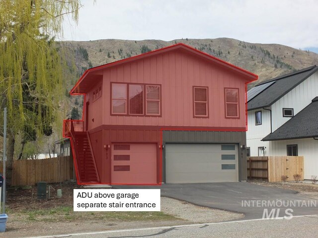 701 N 2nd Ave, Hailey, ID 83333 - view of front of house featuring board and batten siding, fence, a mountain view, aphalt driveway, and an attached garage