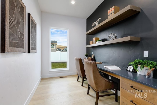 home office featuring light hardwood / wood-style floors and built in desk