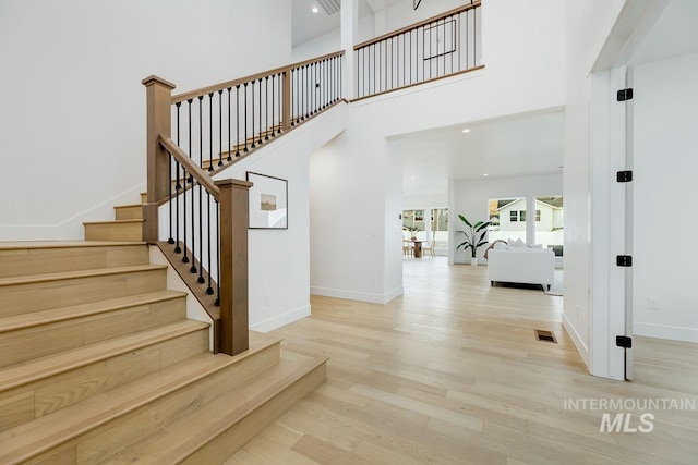 stairway featuring a towering ceiling and hardwood / wood-style flooring