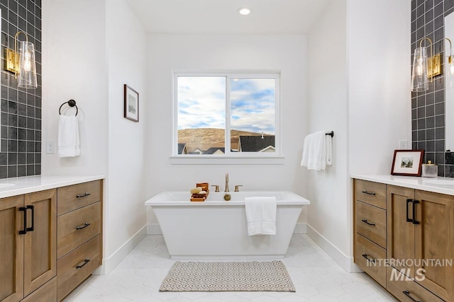 bathroom with a washtub, vanity, and tile patterned flooring